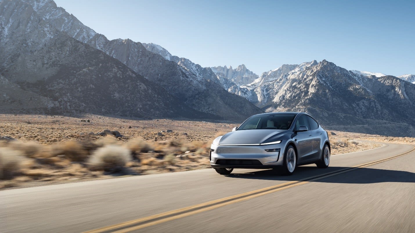 Dağlık bir yolda ilerleyen yeni gümüş Tesla Model Y